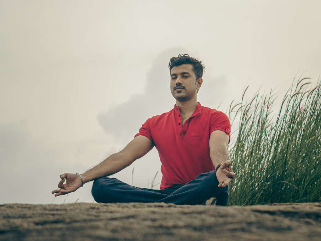 An image of a man performing Heartfulness meditation outdoors.